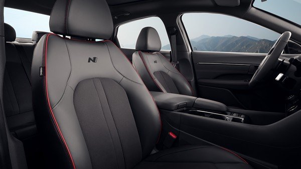 Сәнделген қызыл тігісі бар орындықтар мен руль дөңгелегі.